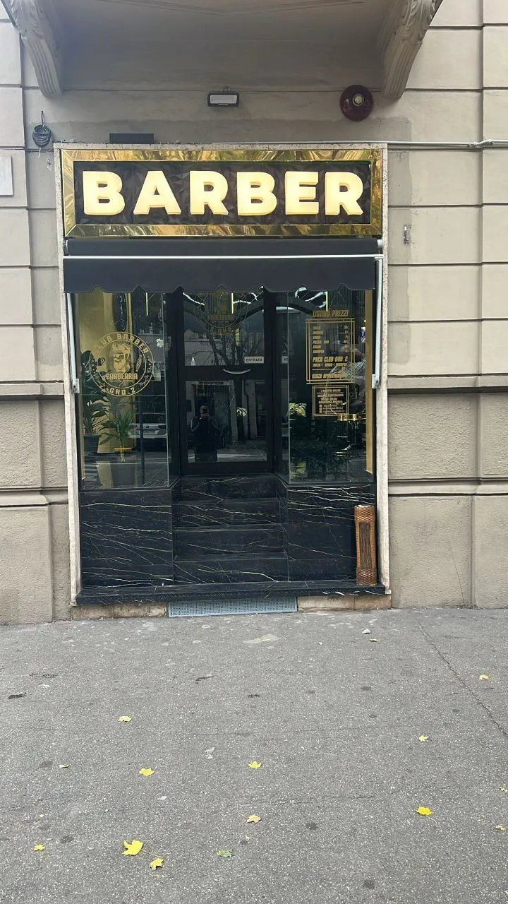 Insegna Barber con lettere in rilievo e cornice dorata sopra la vetrina