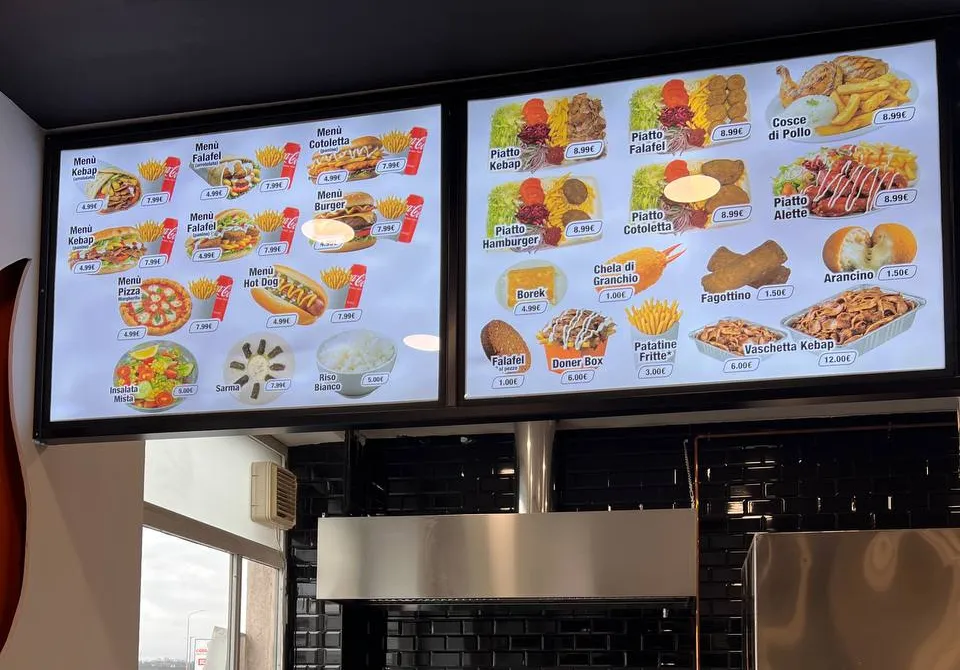 Due pannelli menu retroilluminati sopra il bancone di un locale