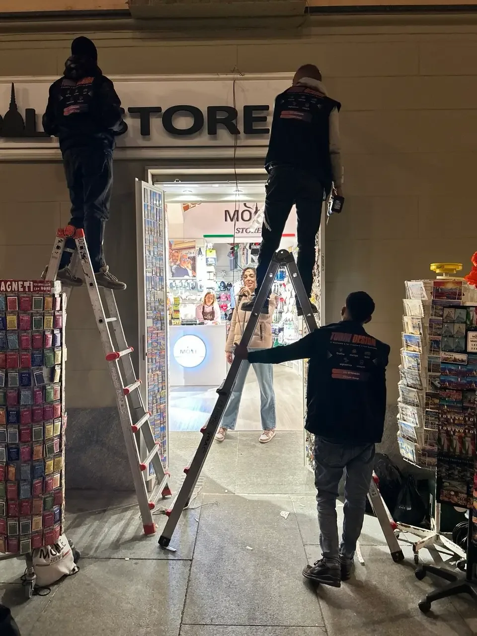 Il team Turin Design monta un’insegna sul fronte di un negozio a Torino